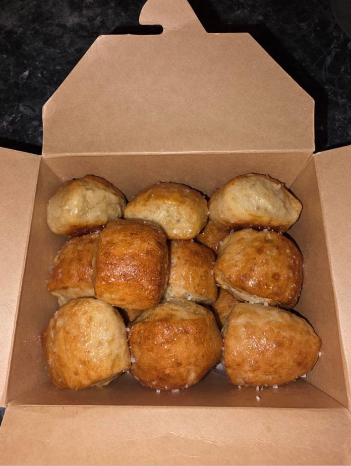 Golden Butter & Salt sourdough pretzel bites topped with coarse salt in an open kraft takeout box